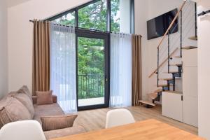 a living room with a couch and a large window at Być Morze in Pobierowo