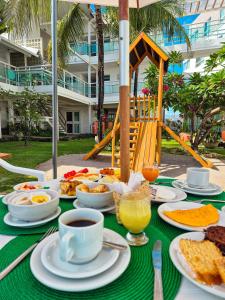 a table with food and coffee on a green table cloth at Hotel Vivenda dos Corais in Porto De Galinhas
