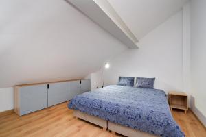 a white bedroom with a bed with a blue comforter at Być Morze in Pobierowo