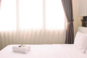 芝卡朗Cozy and Comfort Living 1BR at Oasis Cikarang Apartment By Travelio的一张带两条毛巾的床和窗户