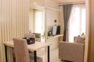 芝卡朗Cozy and Comfort Living 1BR at Oasis Cikarang Apartment By Travelio的带桌椅和电视的客厅