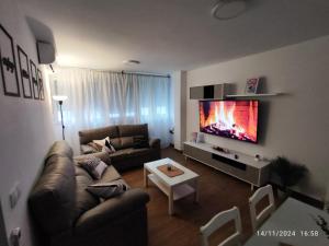 a living room with a couch and a flat screen tv at CITYHOUSE! NUEVO REFORMADO CONFORT WIFI TV65 AC FULL Visco in San Fernando