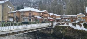 a house on a bridge over a river with snow at Le Porteur de Glace Classé 2 étoiles in Aulus-les-Bains