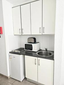 a kitchen with a microwave and a sink at The Poolside Haven, Azure Dreams in Los Cristianos
