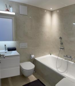 Un baño con bañera, inodoro y lavabo. en Residenza Buca 10 by Fewotessin, en Losone