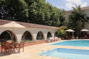 a swimming pool with chairs and a table and umbrella at Hotel Atlântico Praia Cassino Rio Grande in Cassino
