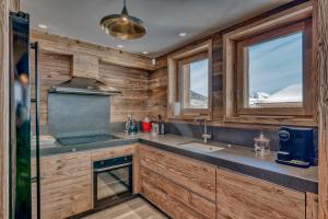 a kitchen with wooden walls and a sink and windows at Chalet des rêves in Megève