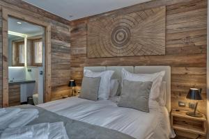 a bedroom with a bed with a wooden wall at Chalet des rêves in Megève