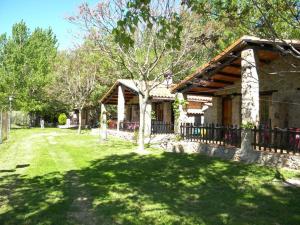 a house with a fence next to a yard at Camping Bungalows Rio Jerte in Navaconcejo