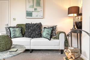 a living room with a white couch with pillows at Coronation Cottage - With Woodfired Hot Tub in Leigh