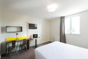 a hotel room with a bed and a desk with a computer at Westlodge Dardilly Lyon Nord in Dardilly