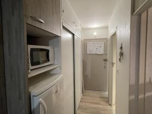 eine kleine Küche mit Mikrowelle und ein Flur in der Unterkunft Studio rénové avec balcon, au pied des pistes, accès WIFI - FR-1-787-53 in Laveissière