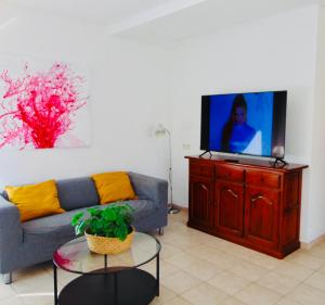 a living room with a couch and a flat screen tv at Casita Playa Castillo "Vivienda 6" in Caleta De Fuste