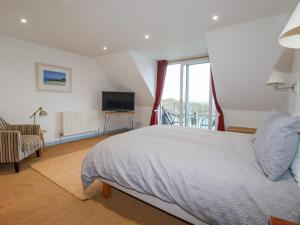 Schlafzimmer mit einem Bett, einem TV und einem Balkon in der Unterkunft Catch the Wave in Newquay