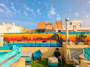 a person sitting on the side of a building with a mural at Daydream Medano Coliving in El Médano