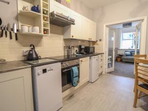 a kitchen with white cabinets and a stove top oven at Charleston Cottage in Bridport