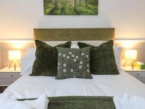 a bedroom with a white bed with green pillows at Charleston Cottage in Bridport