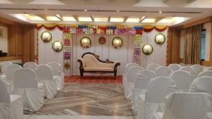 a room with a bunch of white chairs and a couch at Hotel Aishwaryaa in Erode
