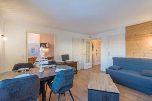 un soggiorno con un divano blu e un tavolo di Appartement Cimes Étoilées - Welkeys a Megève