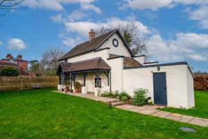ein kleines weißes Gebäude mit schwarzem Dach in der Unterkunft The Garden Cottage in Craven Arms