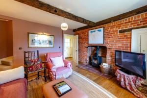 ein Wohnzimmer mit einem gemauerten Kamin und einem TV in der Unterkunft The Garden Cottage in Craven Arms