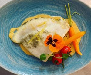 a blue plate with a piece of fish and vegetables at Logis Hôtel Le Bellevue in Les Roches-de-Condrieu