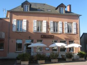 un bâtiment avec des tables et des parasols devant lui dans l'établissement Le Lion D'or, à Ouroux