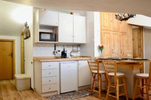 une cuisine avec des armoires blanches et une table et des chaises dans l'établissement Hostdomus - Rifugio delle Stelle, à Sestrières