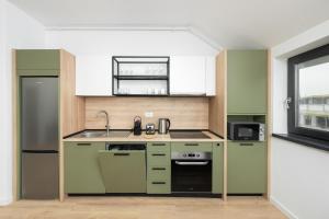 a kitchen with green cabinets and a sink at ELIZA Apartments - powered by NEO - private parking in Timişoara