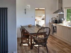 a kitchen with a wooden dining table and chairs at Finest Retreats - Beach Cove in Hodgeston