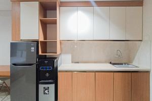 a kitchen with white cabinets and a refrigerator at Homey Studio at Patraland Amarta Apartment By Travelio in Beran-kidul