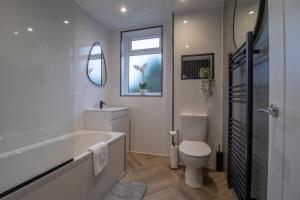 a bathroom with a tub and a toilet and a window at Westlea House in Airdrie +33 photos