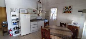 a kitchen with a table and a white refrigerator at Sol y Paz Valle Grande San Rafael in San Rafael