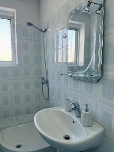 a white bathroom with a sink and a mirror at Ela guest house in Vlorë