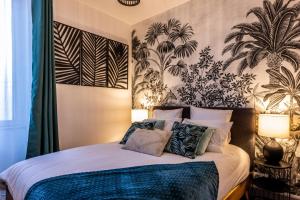 a bedroom with a bed with two lamps and plants on the wall at Major d'Home Amalgame avec jacuzzi en option in Périgueux