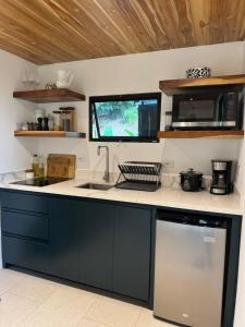 a kitchen with a counter with a sink and a microwave at Casa Rucca in Uvita