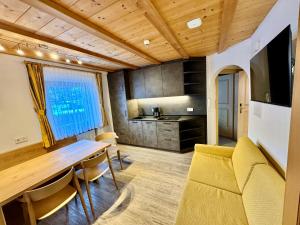a living room with a wooden table and a kitchen at Residence Palmai in Ortisei