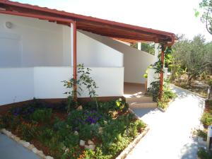a garden in front of a building with flowers at Pansion Comfort Sidro in Novalja