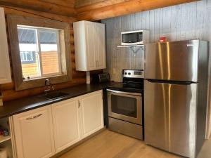 a kitchen with a stainless steel refrigerator and a microwave at Lofted log cabin with fire table in Kelowna