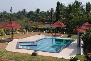 a swimming pool at a resort with umbrellas at Sneha Farm House in Kudāl