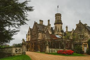 an old castle with red flowers in front of it at Manor by the Lake in Cheltenham