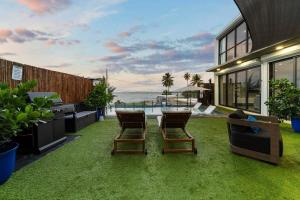 une cour avec deux chaises et une table ainsi qu'une maison dans l'établissement Featuring a breathtaking infinity pool and a beach tennis court, à Loiza