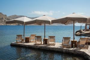 a group of chairs and umbrellas on a dock in the water at Amalthea Luxury Suites in Symi