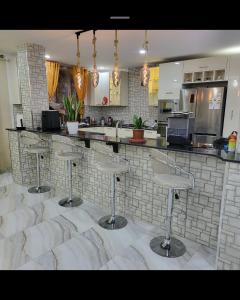 a kitchen with four bar stools in front of a counter at Large two story house in Le Hamiz
