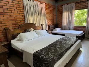 a bedroom with two beds and a brick wall at Hotel Campestre UMPALÁ in San Gil +71 photos