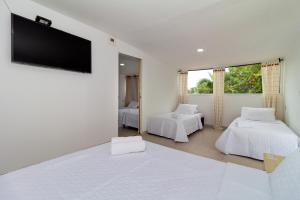 a white room with two beds and a flat screen tv at Hotel Arena Beach Cartagena in Cartagena de Indias +75 photos