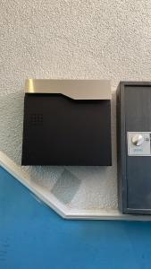 ein schwarzes Gerät auf einem Regal neben einer Wand in der Unterkunft Zimmer in Kaiserslautern in Kaiserslautern