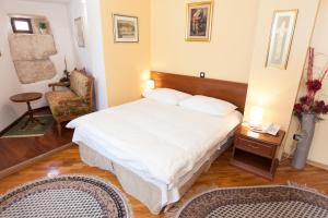 a bedroom with a large white bed and a chair at Hotel Peristil in Split