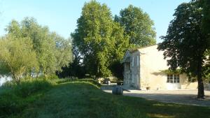 a building with a tree next to a road at Chateau de la Vieille Chapelle in Lugon et l’Ile du Carney