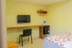 ein Zimmer mit einem Schreibtisch mit Fernseher und einem Stuhl in der Unterkunft Kanoas Suites in São José da Coroa Grande